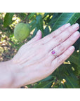 Women's 14k white gold ring with a deep red ruby and trillion side diamonds on a hand.