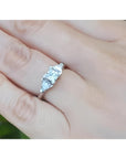 14K white gold ring with a princess cut diamond flanked by two trillion side diamonds on a hand.