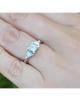 14K white gold ring with a princess cut diamond flanked by two trillion side diamonds on a hand.