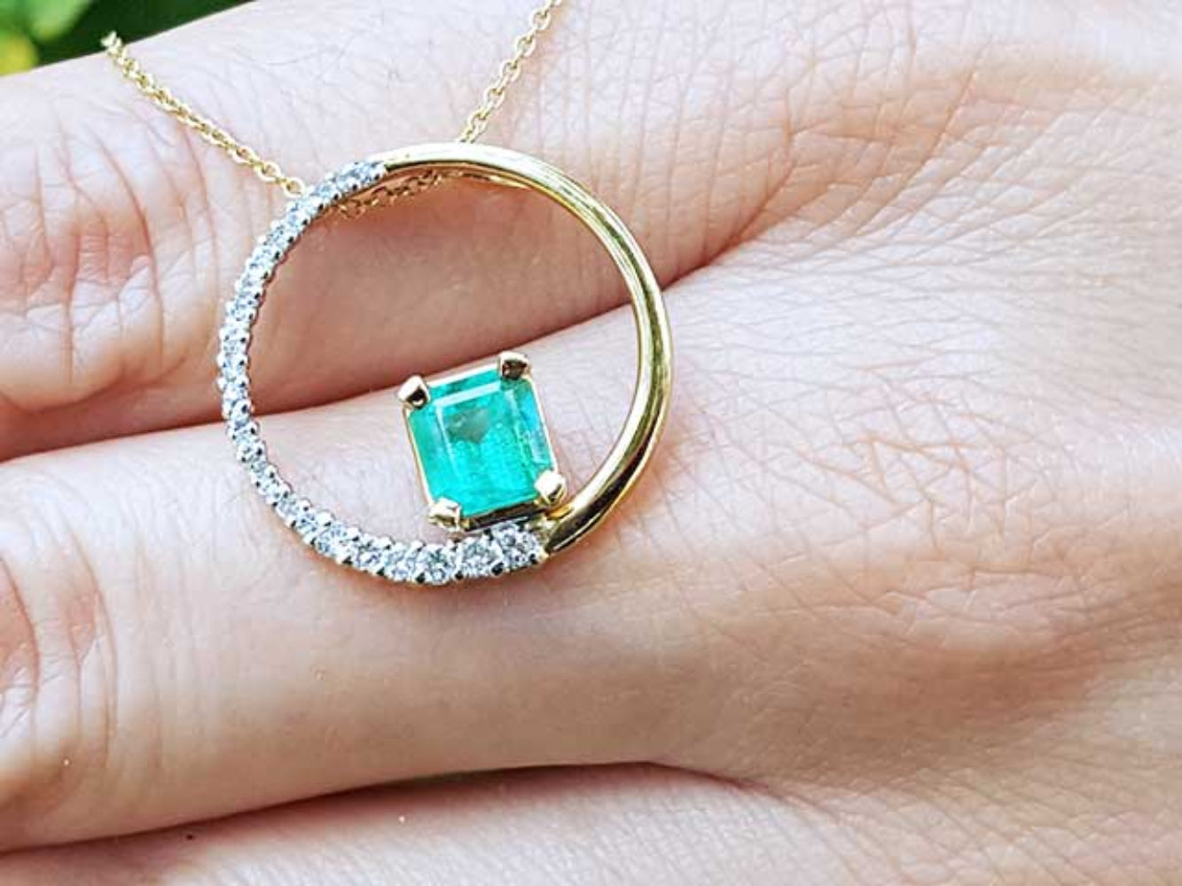 Emerald Bridal circle of life pendant necklace held in a hand