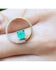 14K gold circle pendant with a 1.08 ct emerald center stone and half pavé natural diamonds.