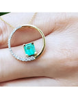 14K gold circle pendant with a 1.08 ct emerald center stone and half pavé natural diamonds.