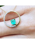 14K gold circle pendant with a 1.08 ct emerald center stone and half pavé natural diamonds.