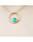 14K gold "Circle of Life" pendant with a rectangular emerald center stone and half pavé diamonds.