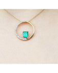 14K gold "Circle of Life" pendant with a rectangular emerald center stone and half pavé diamonds.