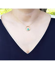 14K gold "Circle of Life" emerald pendant with diamonds, worn on a woman's neck.