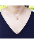 14K gold "Circle of Life" emerald pendant with diamonds, worn on a woman's neck.