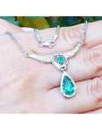 14K white gold necklace with a pear-shaped emerald pendant surrounded by diamonds.