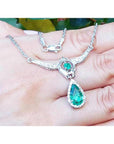 14K white gold necklace with a pear-shaped emerald pendant surrounded by diamonds.