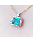 1.31 ct emerald-cut Muzo Colombian emerald necklace with diamond halo on 14K yellow gold chain.