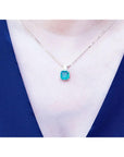 Necklace with an Asscher cut natural Colombian emerald pendant on a person wearing a blue top.