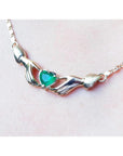 A close display of a hearth cut necklace Claddagh natural emerald Muzo mines crafted in 14k yellow gold