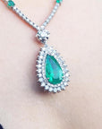 closer view of an emerald necklace with a green teardrop pendant on a women's neck