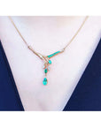 A close view of a yellow gold necklace with natural emeralds gemstones and diamonds worn by a woman