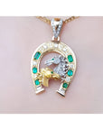 18K yellow gold horseshoe pendant with emeralds, diamonds, and two horse heads.