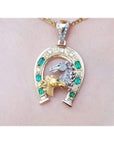 18K yellow gold horseshoe pendant with emeralds, diamonds, and two horse heads.
