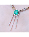 Closer right side view of a kisses and hugs necklace with a center natural square emerald on woman's collar