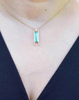Emerald baguette cut necklace with natural diamonds, 14K yellow gold, worn on a person.