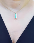 Emerald baguette cut necklace with natural diamonds, 14K yellow gold, worn on a person.