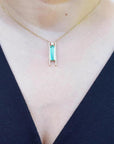 Emerald baguette cut necklace with natural diamonds, 14K yellow gold, worn on a person.