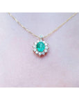 A closer view of a yellow gold necklace with a natural Muzo emerald gemstone pendant on a women's neck