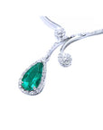 A closer left side view of a white gold necklace with a genuine teardrop emerald pendant on a white background