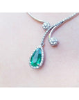Elegant white gold necklace with a teardrop-shaped emerald pendant into halo diamond on lady's collar
