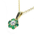 18K yellow gold cluster pendant with a center diamond surrounded by emeralds on a chain.