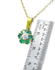 Gold emerald and diamond cluster pendant necklace and a ruler for scale.