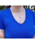 18K yellow gold cluster emerald and diamond pendant necklace on a woman in a blue shirt.