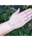 14K yellow gold bracelet with a central emerald and diamond cluster on a woman's wrist.