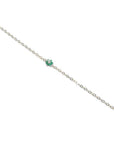 14K yellow gold bracelet with a central cluster of six green emeralds and one diamond.