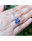 A cluster of natural sapphires pendant white gold necklace displayed on a person's hand