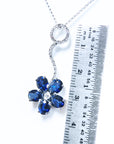 A cluster of natural sapphires pendant white gold necklace nest to a ruler for measure