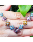 18K white gold X-cluster necklace with tri-colored topaz and diamond links on a hand.