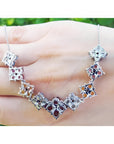 18K white gold X-cluster necklace with tri-colored round-cut natural topaz and diamond links on a hand.