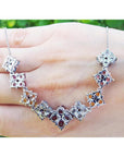 18K white gold X-cluster necklace with tri-colored round-cut natural topaz and diamond links on a hand.