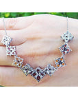 18K white gold X-cluster necklace with tri-colored round-cut natural topaz and diamond links on a hand.