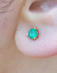 close-up of a earlobe dressing a cocktail emerald stud earring.