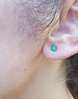 Close-up of a woman ear dressing a Colombian emerald cocktail earring.