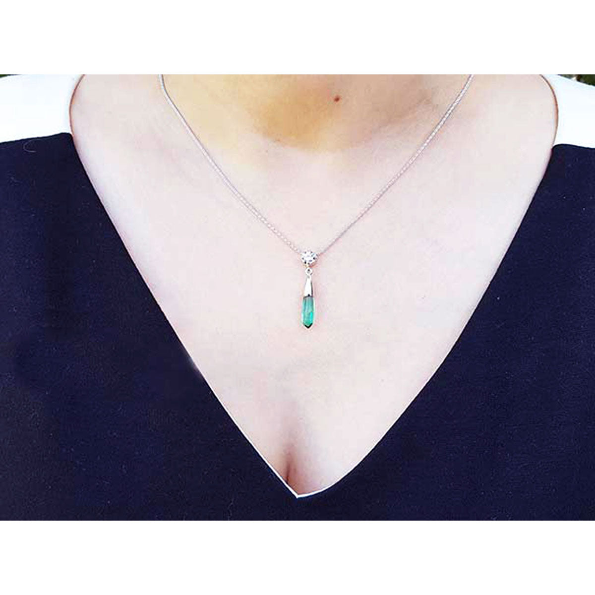 White gold 14k emerald briolette necklace with a pendant worn by a person in a dark blue top.