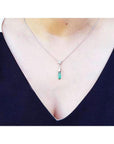Colombian emerald briolette necklace with a diamond slider on a 14K white gold chain, worn on a woman's neck.