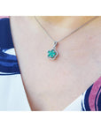 Emerald cluster necklace with diamonds in 14K white gold, clover-like design on a woman's neck.