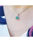 Emerald cluster necklace with diamonds in 14K white gold, clover-like design on a woman's neck.