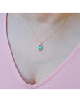 Women's emerald jewelry necklace square emerald-cut, halo diamond 14k yellow gold on a pink top.