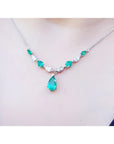 14k white gold necklace with pear-shaped emeralds and diamonds, featuring a large emerald drop.