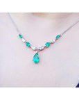 14k white gold necklace with pear-shaped emeralds and diamonds, featuring a large emerald drop.