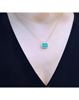 18K yellow gold necklace with a vibrant deep green emerald solitaire in an east-west setting.