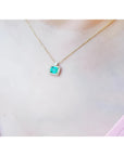 1.31 ct emerald-cut Muzo Colombian emerald necklace with diamonds in 14K yellow gold on a model.