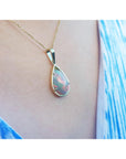 Opal pendant necklace on a person wearing a blue top
